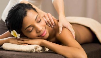 Closeup of happy african woman receiving back massage at salon spa